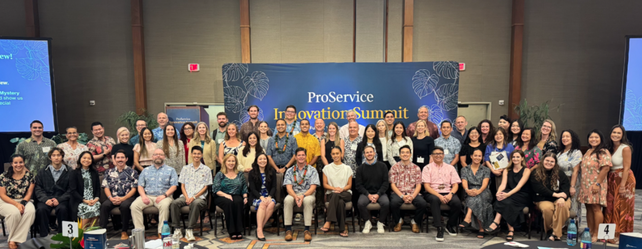 The ProService team and summit attendees gathered for a group photo in front of the ProService Innovation Summit banner